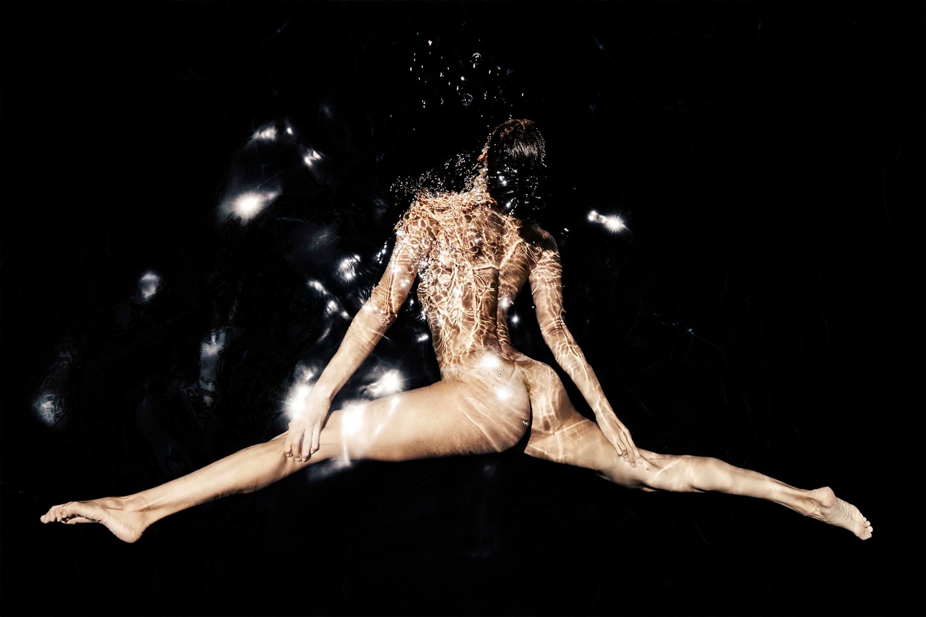 Figure floating in dark water with reflected light across the body
