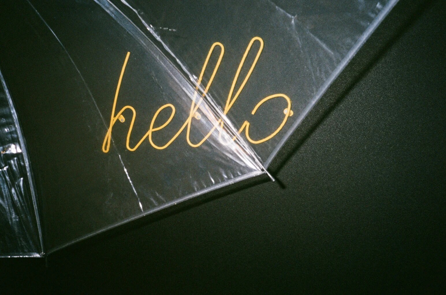 Yellow hello sign seen through a clear umbrella